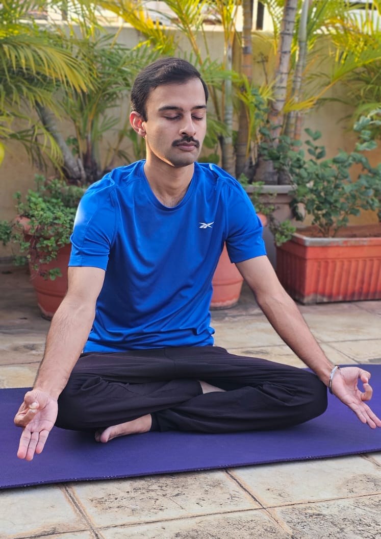 Aditya Bhargava seated in lotus pose on a yoga mat, eyes closed, with palms in chin mudra